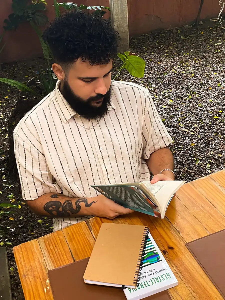 Matheus Bandeira lendo sobre Gestalt-Terapia, ao ar livre